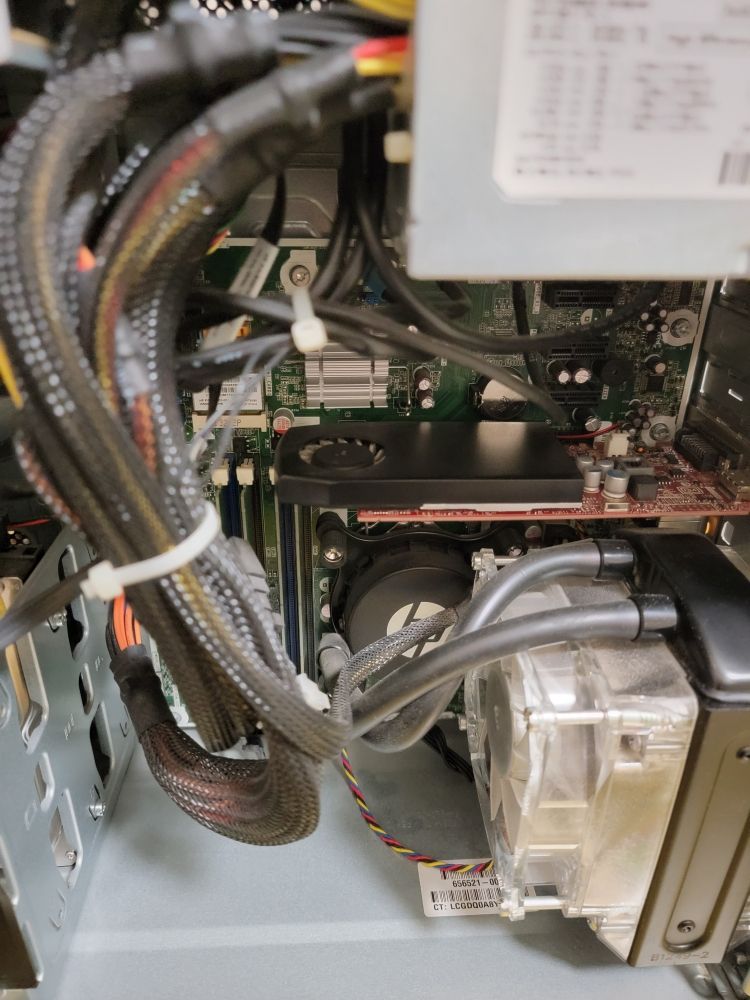 Interior of a desktop tower with cables being routed and tidied around a liquid cooling setup.