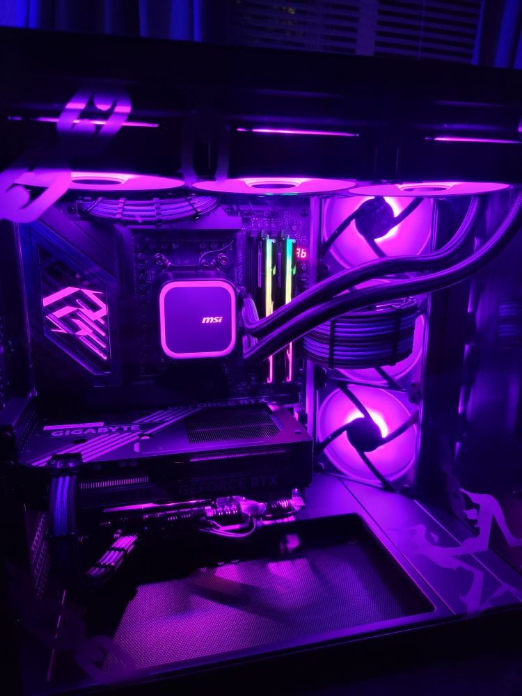 A custom-built desktop PC with purple interior lighting, visible cooling loop, and graphics card.
