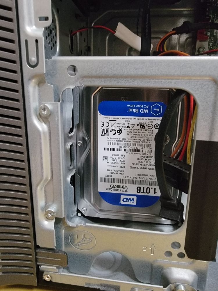 A hard drive being installed into a desktop tower's drive bay.