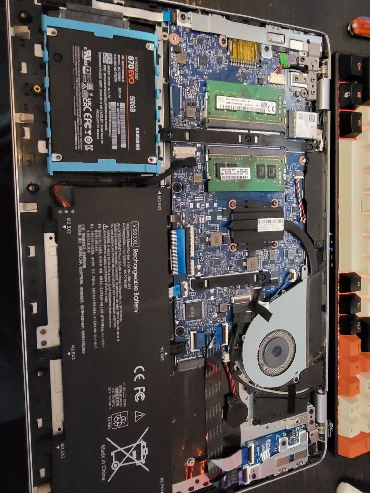 Close-up of a laptop's internals with new memory and a solid-state drive freshly installed.